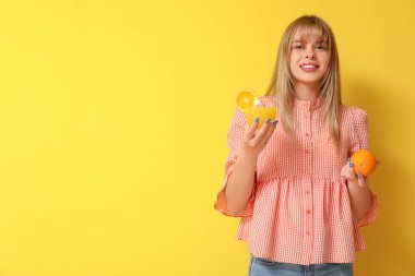 Sarı arka planda portakal suyu bardağı olan genç bir kız.