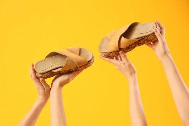 Sarı arka planda parmak arası terlikleri olan eller