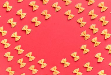 Kırmızı arkaplanda pişmemiş farfalle makarnadan yapılmış çerçeve