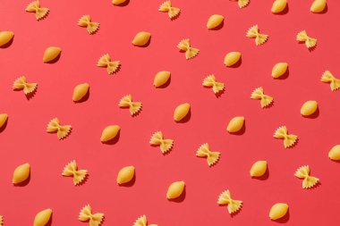 Kırmızı arkaplanda farklı pişmemiş makarna