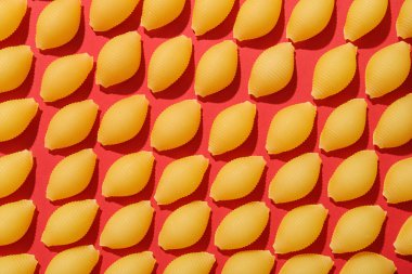 Kırmızı arka planda pişmemiş koni makarna.