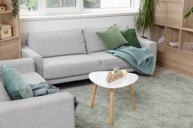 Modaya uygun gri koltukları, raf üniteleri ve masaları olan bir oturma odası.