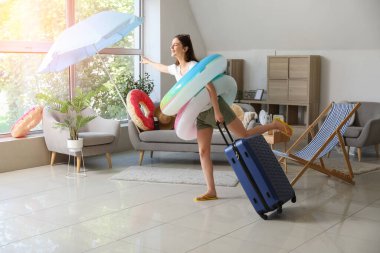 Yüzme yüzükleri ve bavulu olan genç kadın yaz tatiline evde hazır.