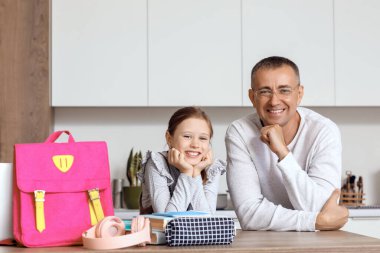 Babası küçük kızına mutfakta okul çantasını toplaması için yardım ediyor.