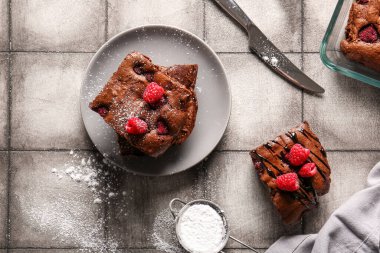 Üzerinde ahududu çikolatalı brownie parçaları olan gri fayanslı bir tabak.