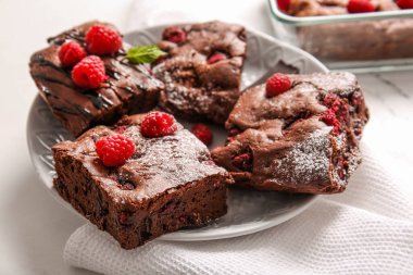 Beyaz arka planda ahududulu çikolatalı browni tabağı.