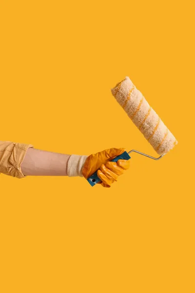Worker with paint roller on yellow background
