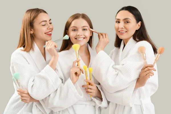 Mulheres Jovens Com Pincéis Maquiagem Fundo Cinza — Fotografia de Stock