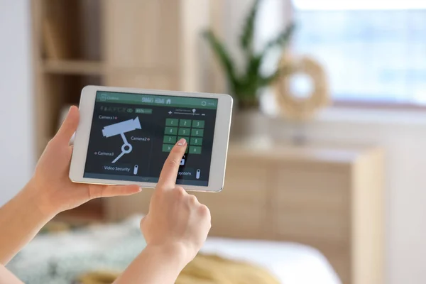 stock image Young woman using smart home security system control panel in bedroom, closeup