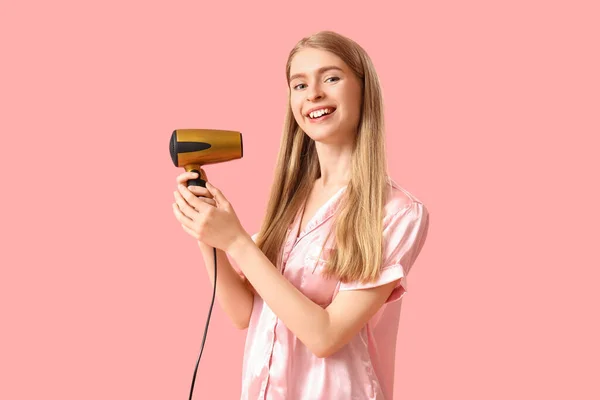 Młoda Blondynka Piżamie Suszarką Włosów Różowym Tle — Zdjęcie stockowe