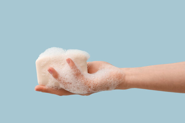 Hand with soap on light blue background