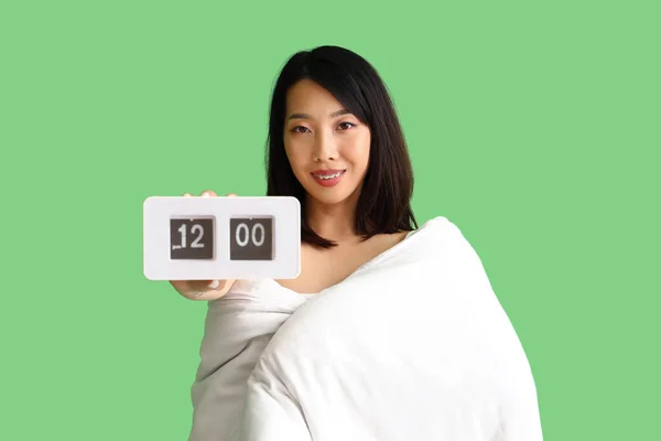 緑の背景に毛布と時計を持つ美しいアジアの女性 — ストック写真