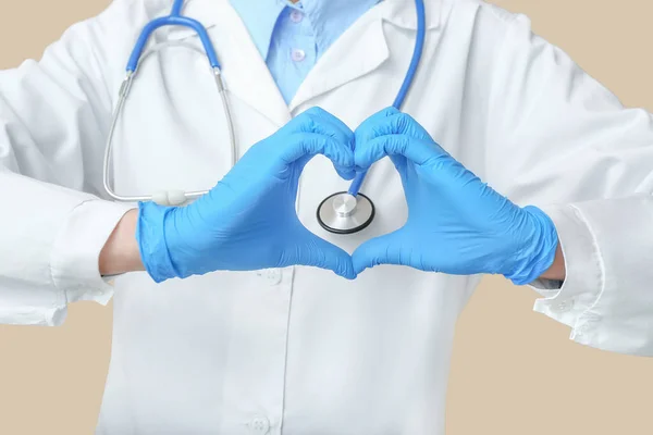 Ärztin Mit Stethoskop Macht Herz Mit Den Händen Auf Beigem — Stockfoto