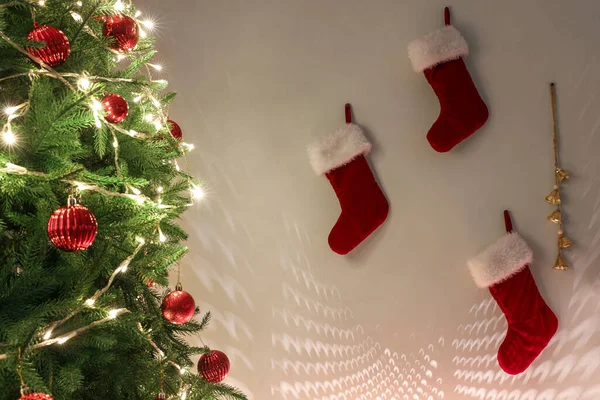 Árvore Natal Com Luzes Brilhantes Bolas Meias Perto Parede Branca — Fotografia de Stock