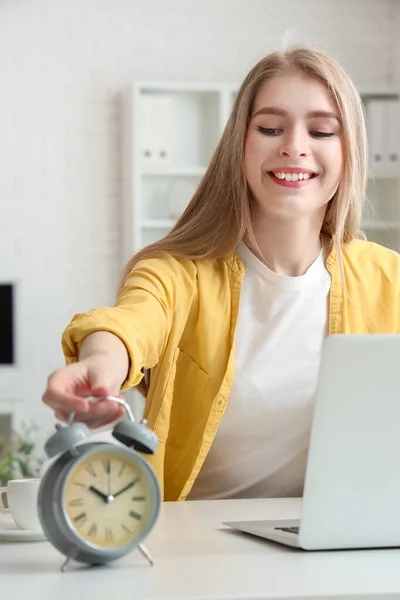 Young businesswoman with alarm clock in office