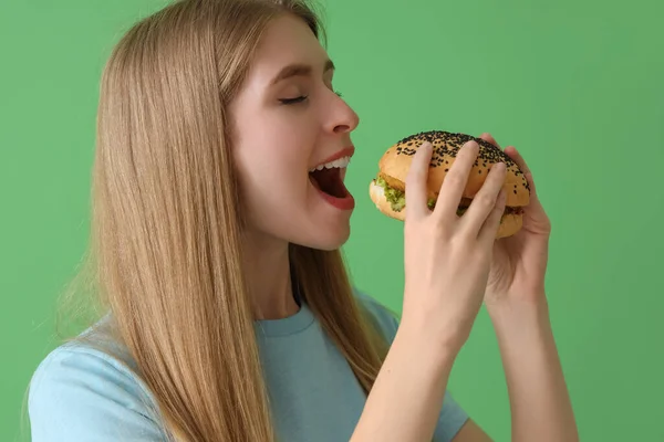 緑の背景においしいハンバーガーを持つ若い女性 クローズアップ — ストック写真
