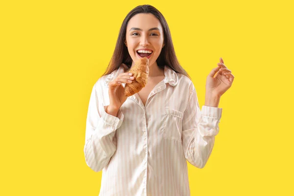 Young Woman Pajamas Tasty Croissant Yellow Background — Stock Photo, Image