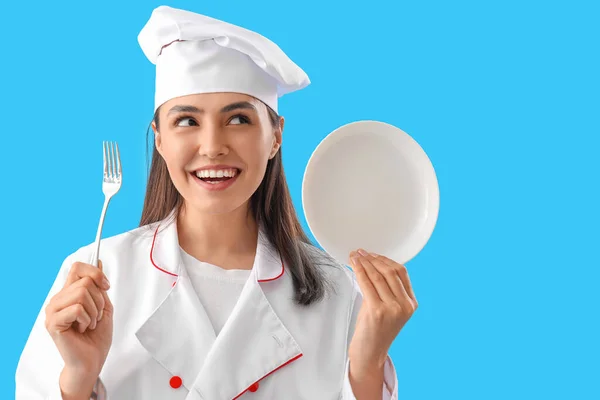 蓝底带叉子和盘子的女厨师 — 图库照片