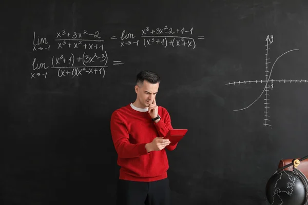 Nachdenklicher Mathelehrer Mit Taschenrechner Neben Tafel Klassenzimmer — Stockfoto
