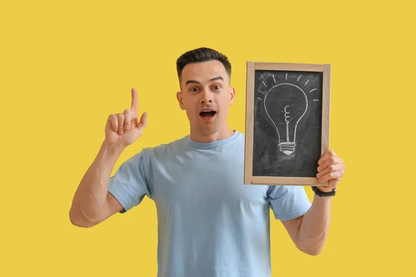 Male Teacher Holding Chalkboard Drawn Light Bulb Yellow Background — Stock Photo, Image