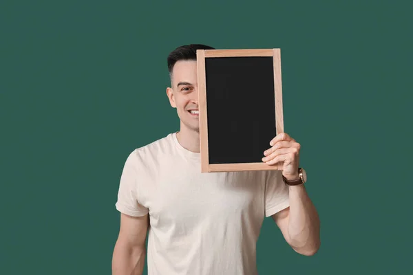 stock image Male teacher with chalkboard on green background