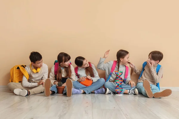 Bej Duvarın Yanında Sırt Çantalı Küçük Öğrenciler Oturuyor — Stok fotoğraf