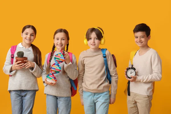 Kleine Schüler Mit Rucksäcken Auf Orangefarbenem Hintergrund — Stockfoto