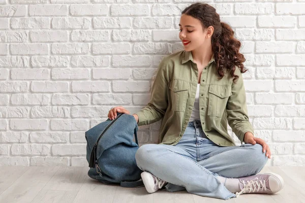 stock image Female student with backpack sitting near white brick wall