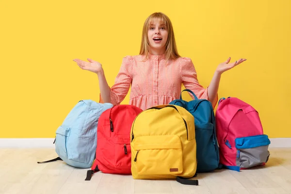 Zaskoczona Studentka Plecakami Siedząca Przy Żółtej Ścianie — Zdjęcie stockowe