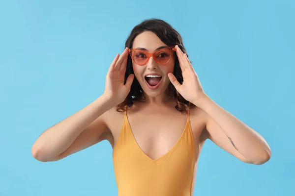 Überraschte Junge Frau Sonnenbrille Und Badeanzug Auf Blauem Hintergrund — Stockfoto