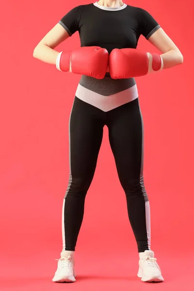 若いです女性でスポーツウェアとボクシング手袋で赤の背景 — ストック写真