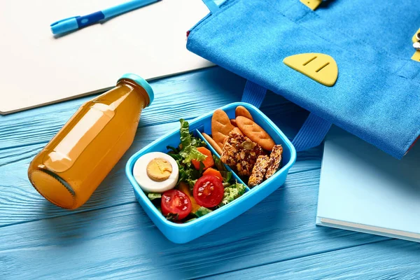 Plecak Papeteria Pudełko Śniadaniowe Smacznym Jedzeniem Niebieskim Drewnianym Tle — Zdjęcie stockowe