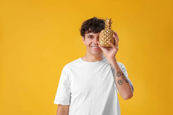 在黄色背景上装饰菠萝的年轻人 — 图库照片