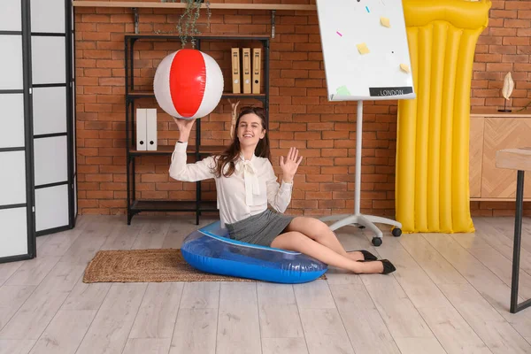 Stock image Young businesswoman with beach ball ready for summer vacation in office