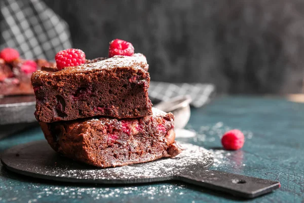 stock image Board with pieces of raspberry chocolate brownie on dark table