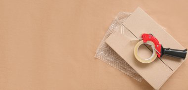 Kağıt arkaplan üzerinde bant dağıtıcısı, karton kutu ve baloncuk ambalajı metin için boşluk ile paketleniyor