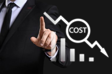 İş adamı karanlık arka planda sanal ekran kullanıyor. Maliyet düşüşü