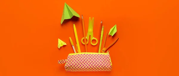 带铅笔盒的纸飞机和橙色背景的学习用品 — 图库照片
