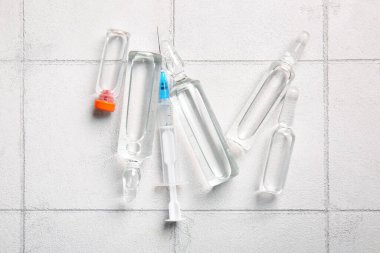 Beyaz karo zemin üzerinde şırınga ile tıbbi ampule