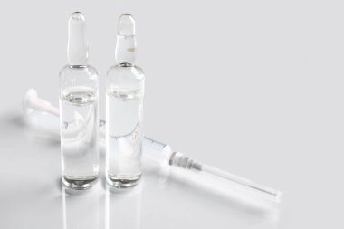 Işık arka planında şırıngası olan tıbbi ampule