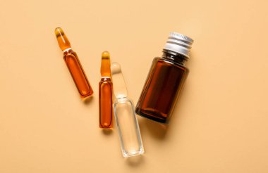 Bej arka planda ilaç bulunan ampuller ve şişeler.