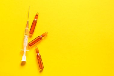 Sarı zemin üzerinde şırınga bulunan ampüller