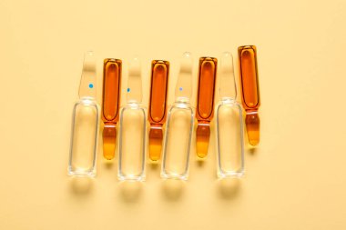 Açık sarı arka planda cam tıbbi ampule.