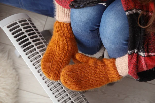 女性在家中靠近散热器的地方用手套暖手 — 图库照片