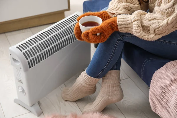 Vrouw Met Kopje Hete Koffie Verwarmen Buurt Radiator Thuis Close — Stockfoto