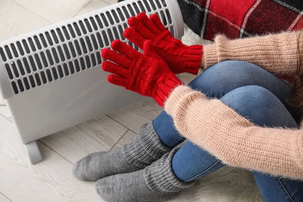 stock image Woman warming hands in gloves near radiator at home, closeup