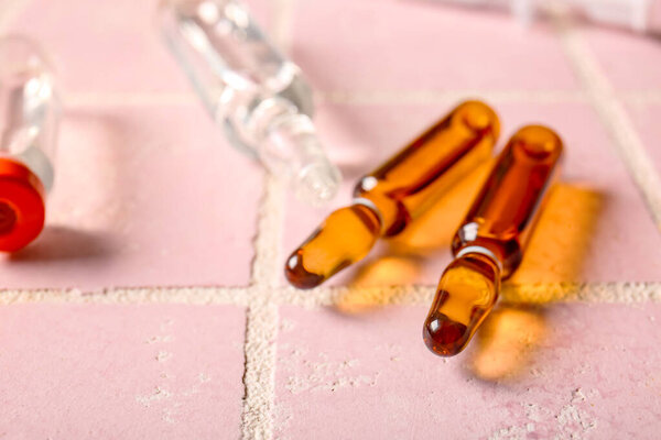 Medical ampules and bottle with medicines on pink tile background