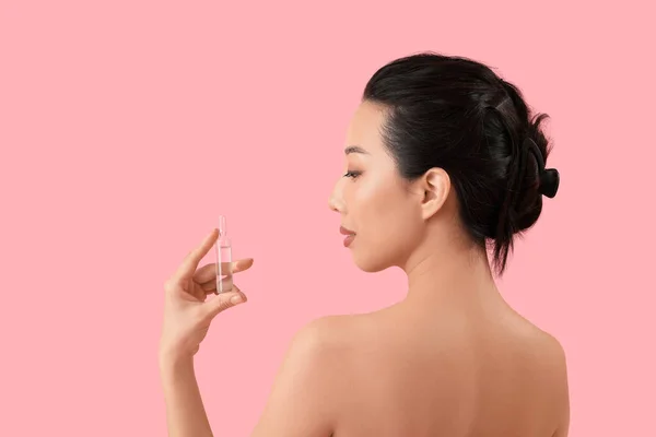 ピンクの背景にアンプルを持つ美しいアジアの女性 スキンケアコンセプト — ストック写真