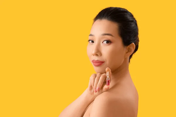 黄色の背景にアンプルと美しいアジアの女性 スキンケアコンセプト — ストック写真