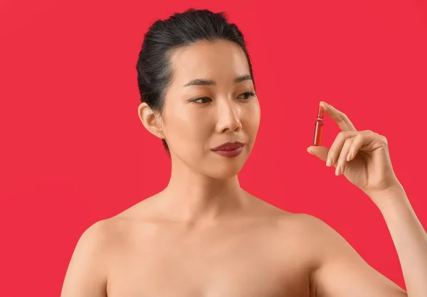 赤い背景にアンプルを持つ美しいアジアの女性 スキンケアコンセプト — ストック写真